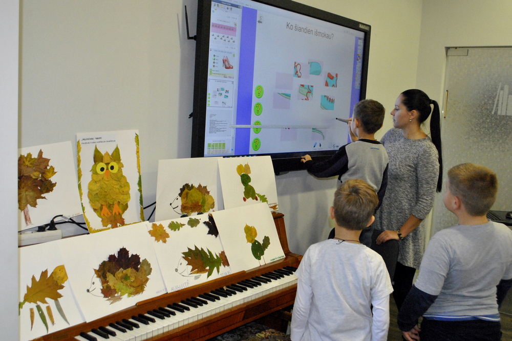 Vaikai sprendžia interaktyvią pamoką ekrane.